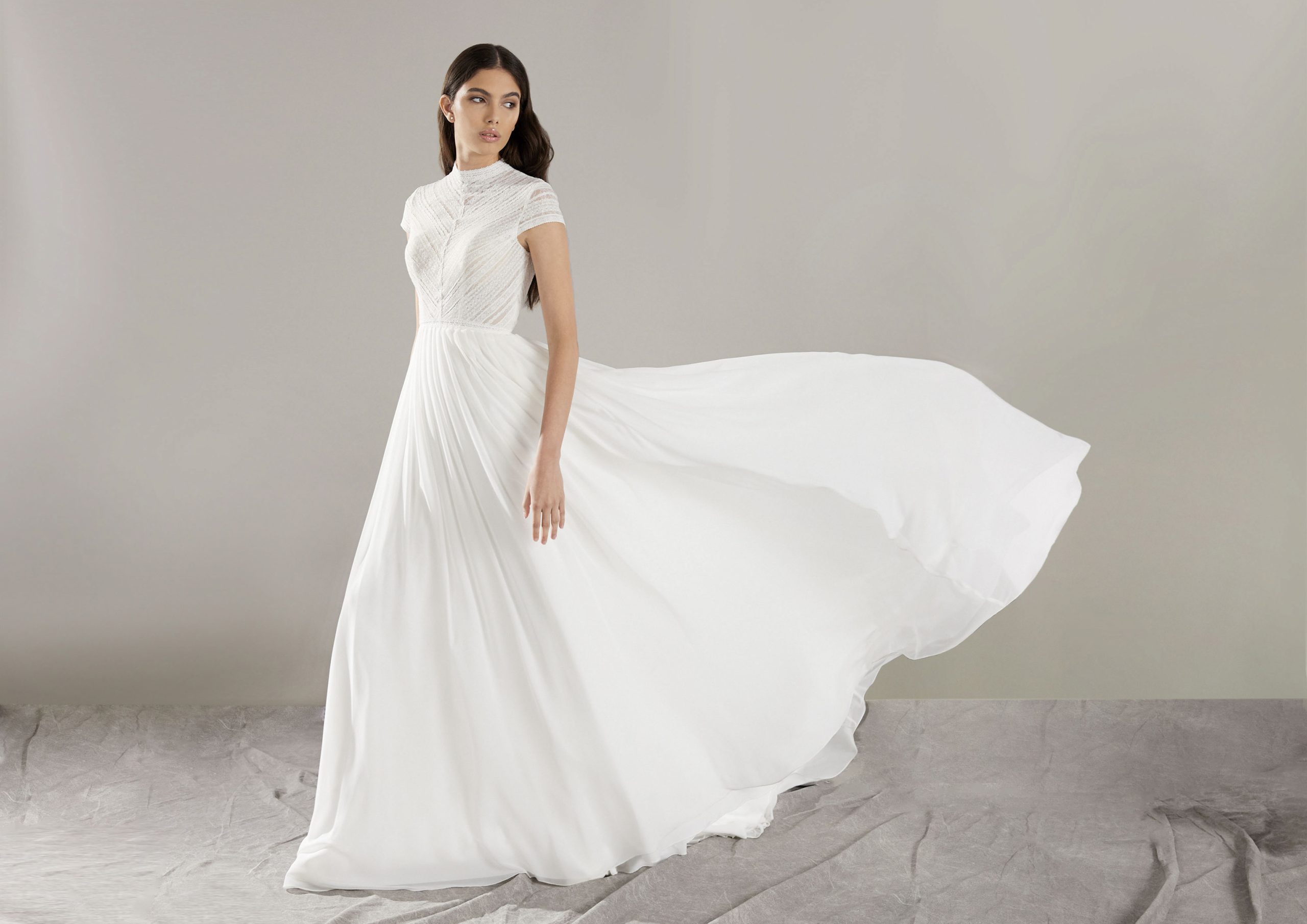 Bruid in a-lijn trouwjurk met zwierige rok en hooggesloten halslijn.