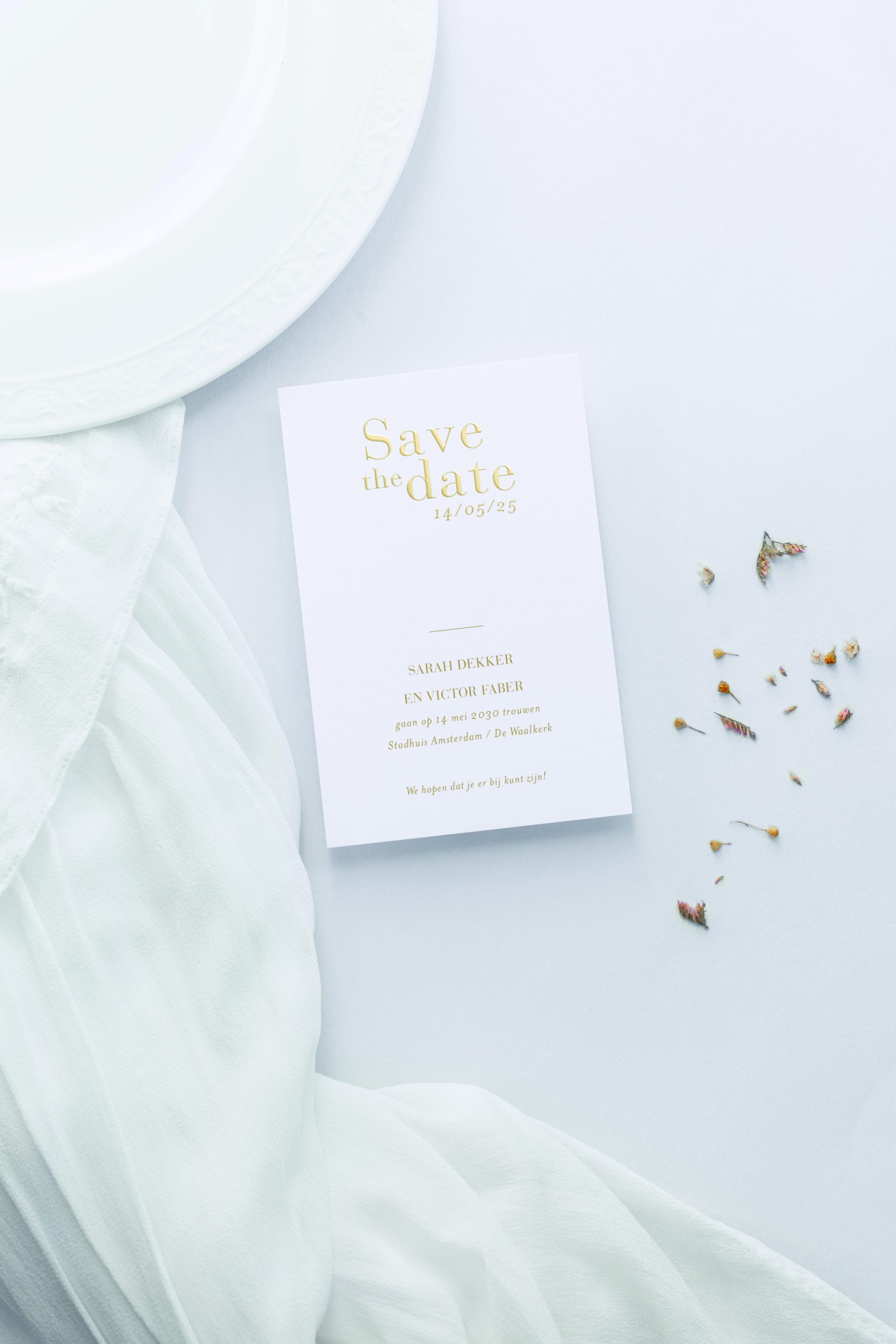 Witte save-the-date-kaart voor een bruiloft met confetti. De tekst op de kaart zijn goude letters