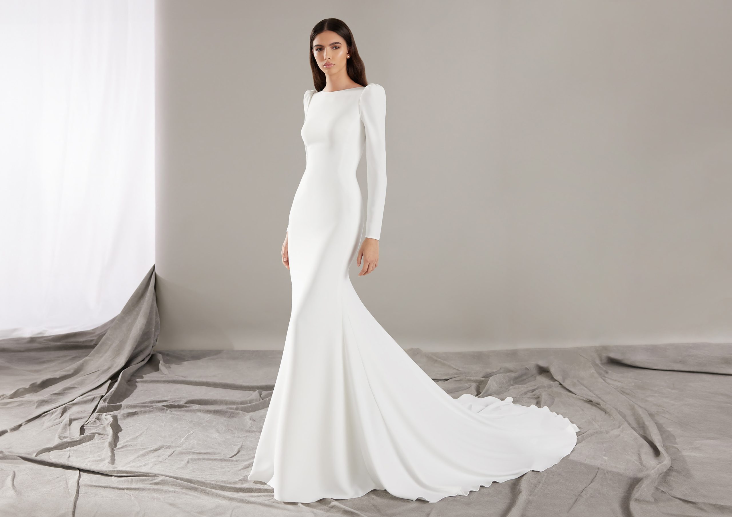 Bruid in fit and flare bruidsjurk, minimalistische stijl en lange mouwen