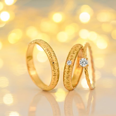 3 gouden trouwringen met gouden glitter achtergrond