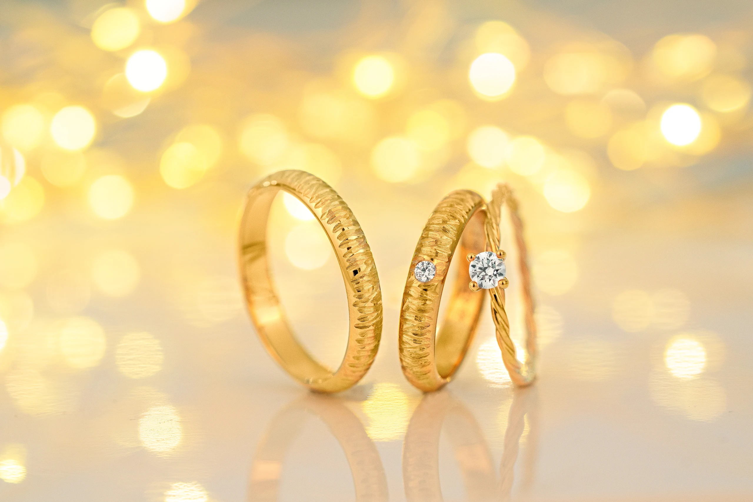 3 gouden trouwringen met gouden glitter achtergrond