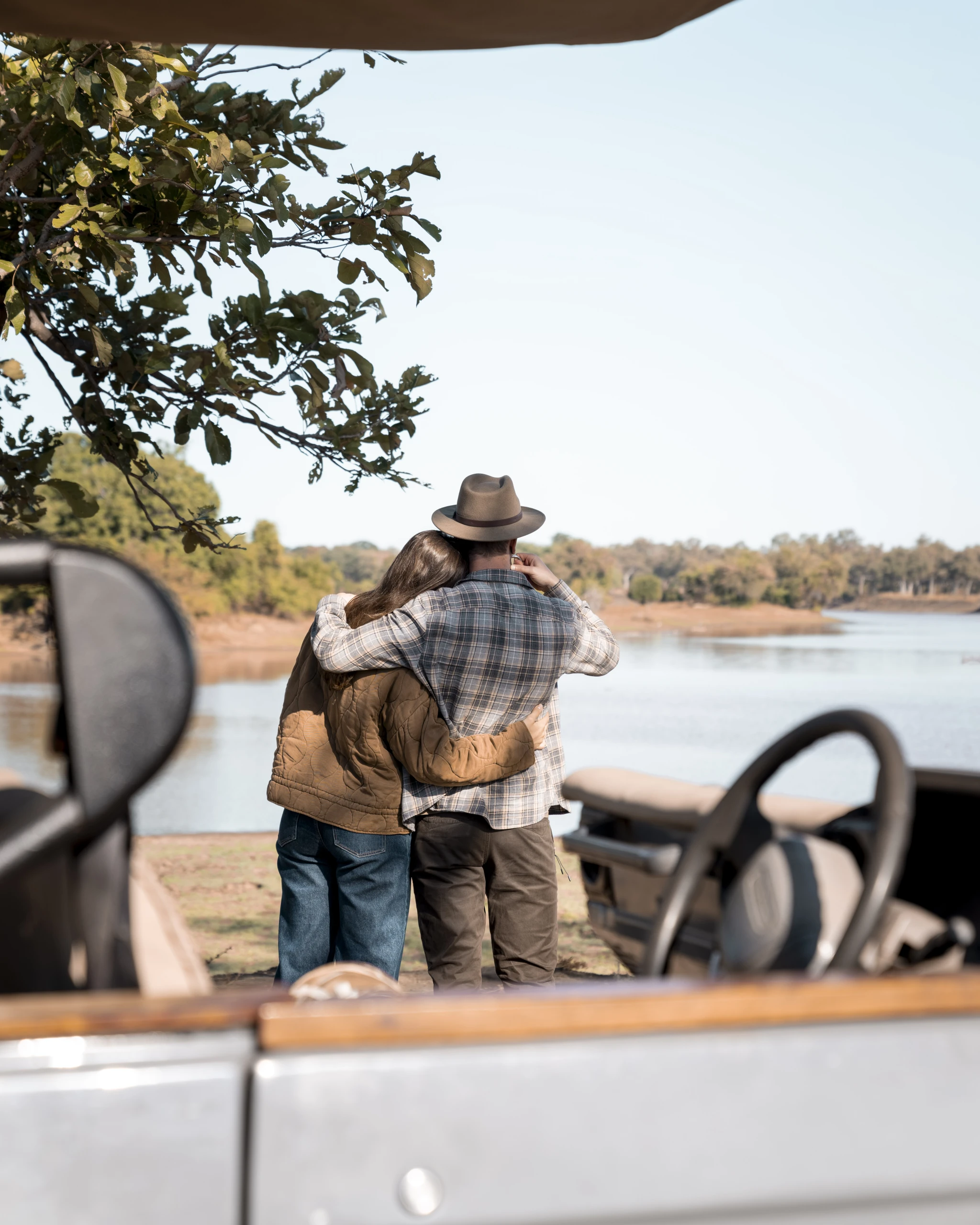 Bruidspaar geniet van hun huwelijksreis met safari-uitzicht aan rivier in Zuid-Luangwa National Park, Zambia – romantisch moment bij koffiestop tijdens safari met 4x4 jeep.