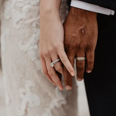 Trouwfoto, bruidspaar hand in hand met trouwringen om