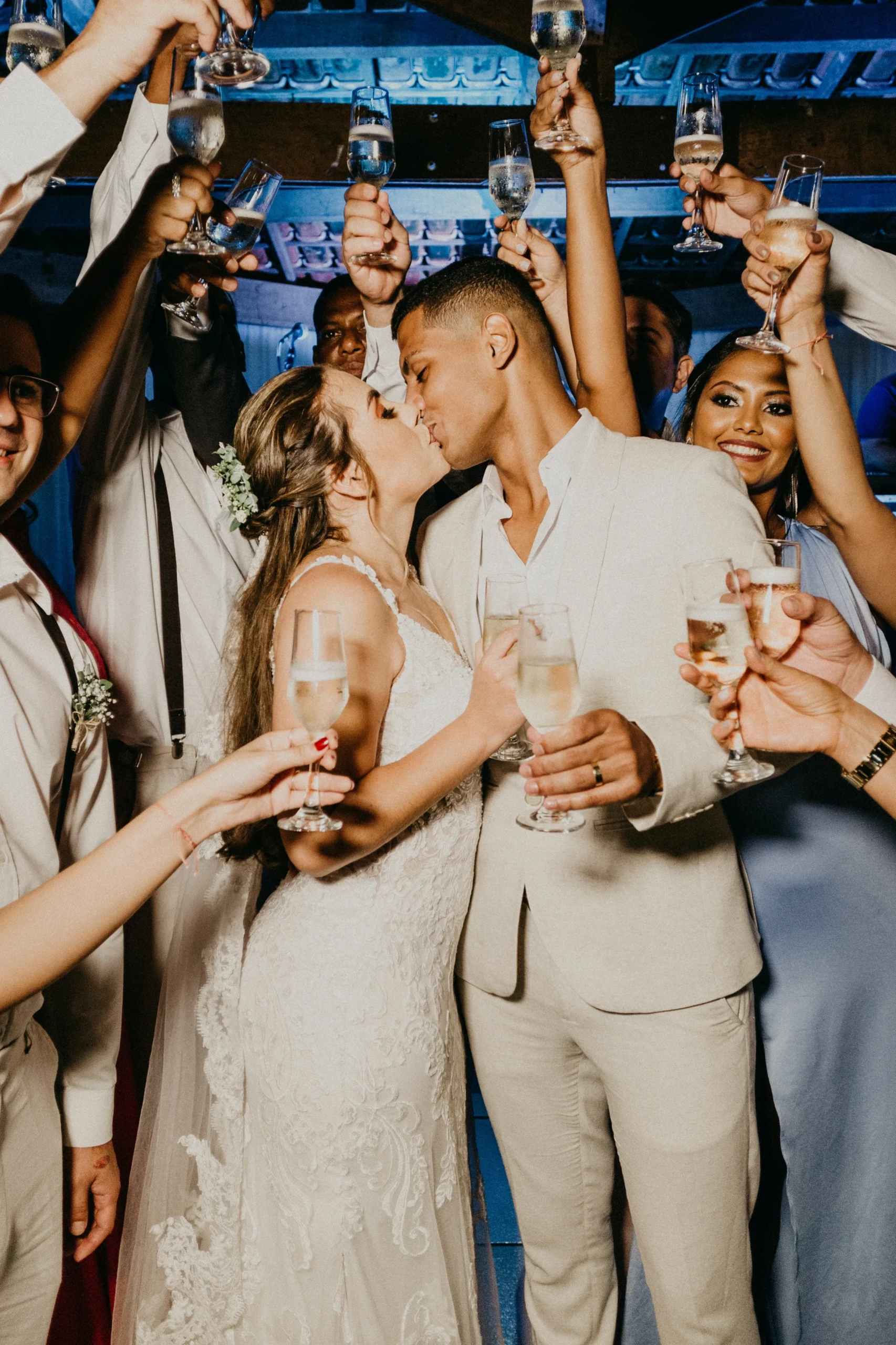 Bruidspaar staat tussen vrienden en familie met champagne op bruiloftsfeest.