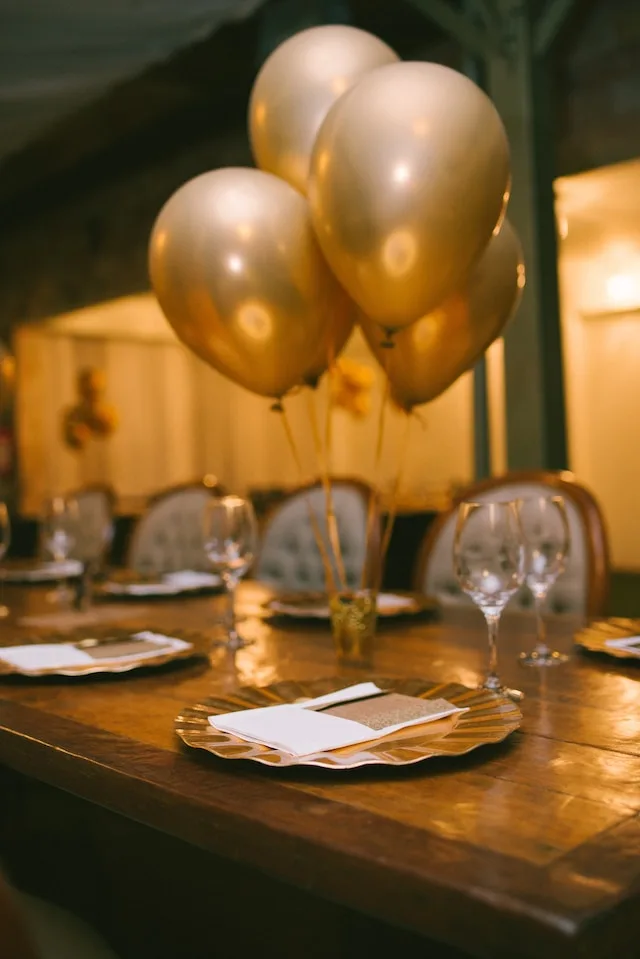 Dinertagel gedekt en versierd met gouden ballonnen.