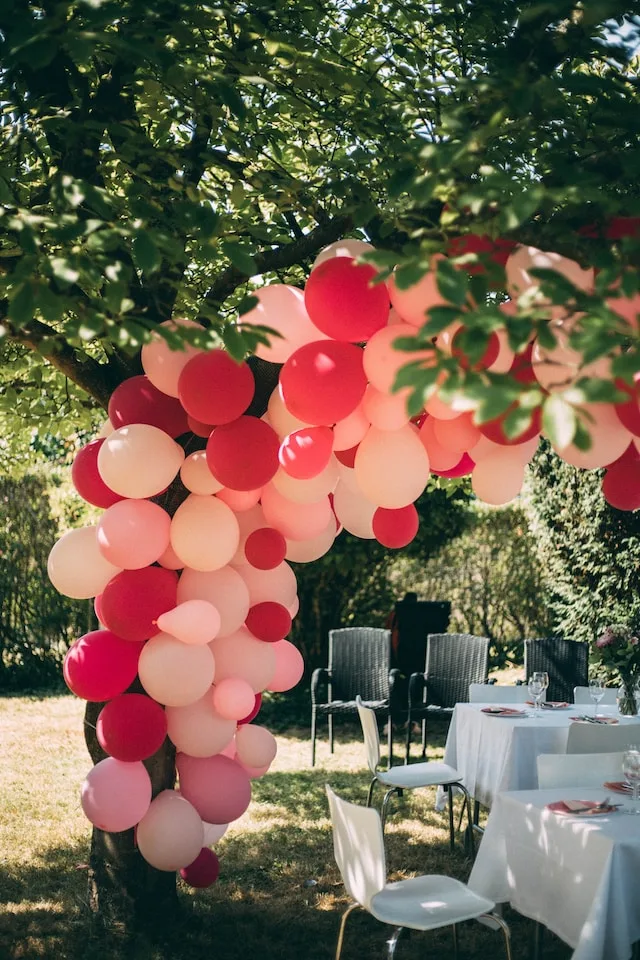 Kleurrijke ballonnenboog op bruiloft met rode en roze ballonnen.