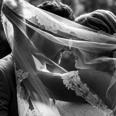 Trouwfoto bruidspaar onder sluier