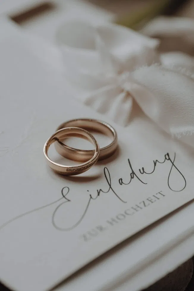Twee trouwringen die op een uitnodiging liggen