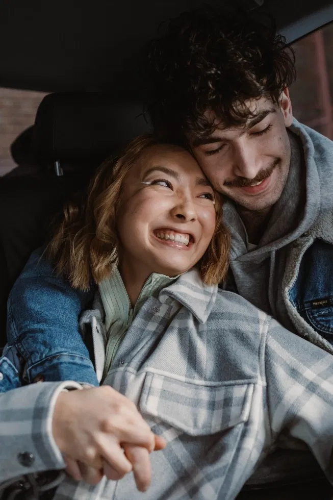 man houdt vrouw vast achterin de auto