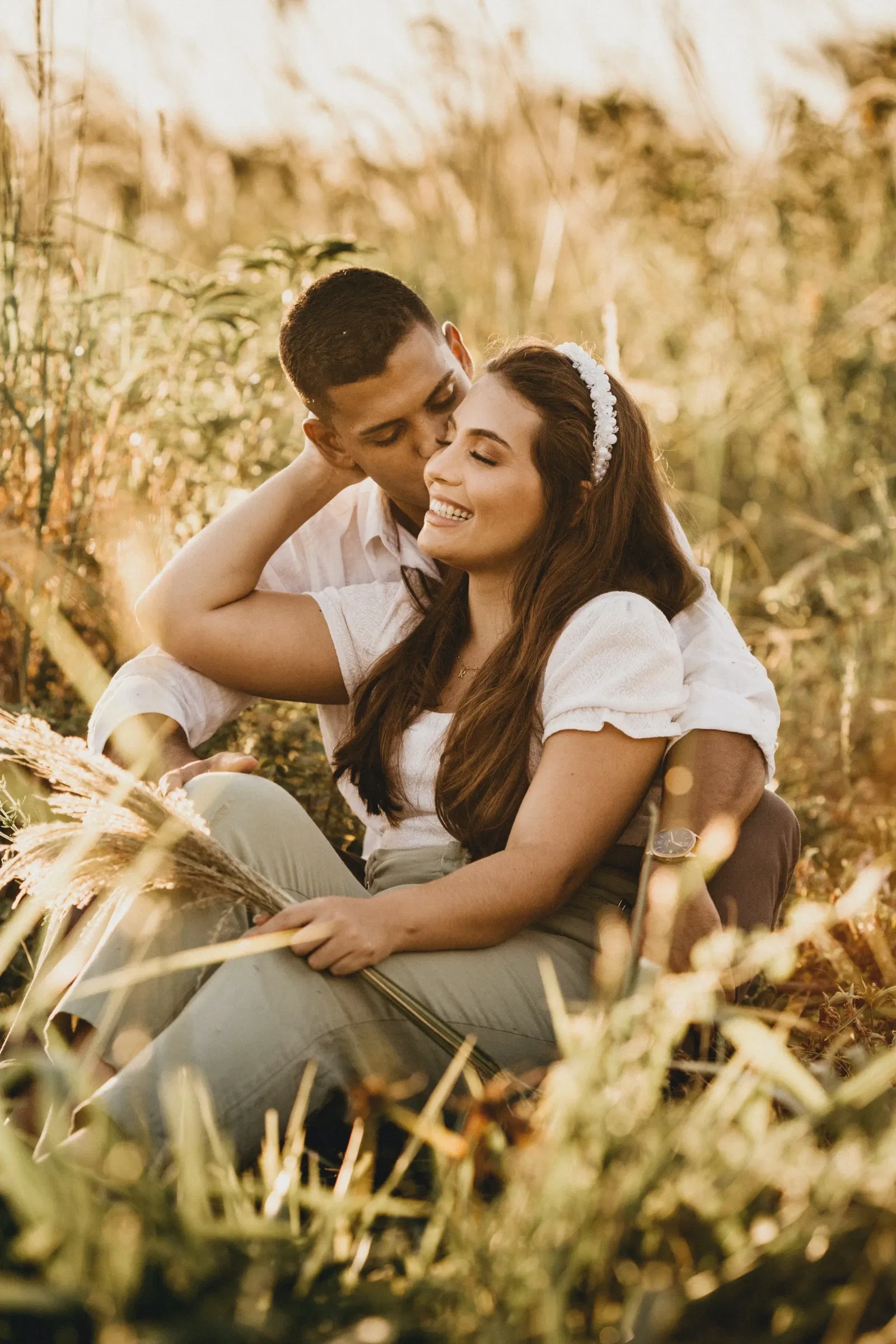 Man en vrouw zitten tussen het riet. De man kust de vrouw op de wang