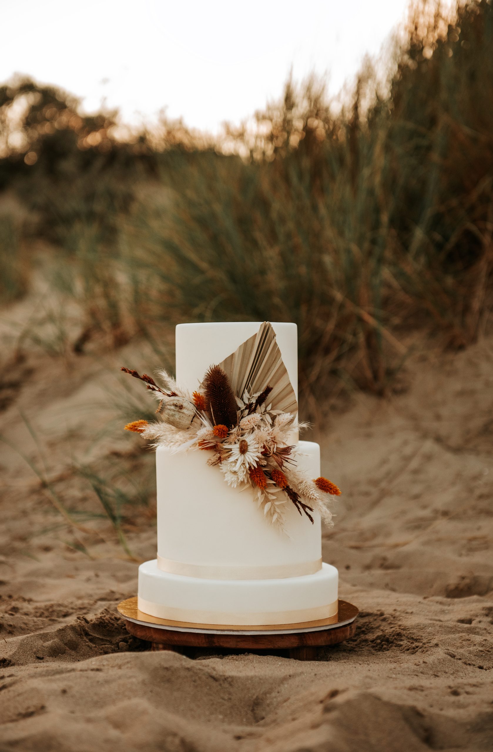 Witte bruidstaart met droogbloemen versiering in de duinen