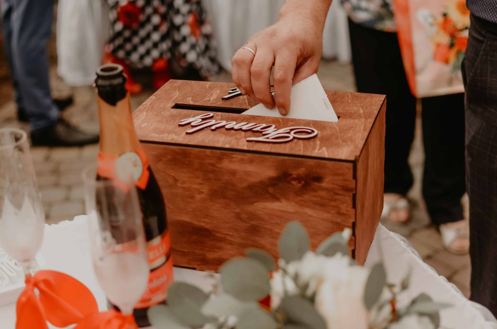 Geld/Brieven box op cadeau tafel van bruiloft waar iemand een envelop in stopt.