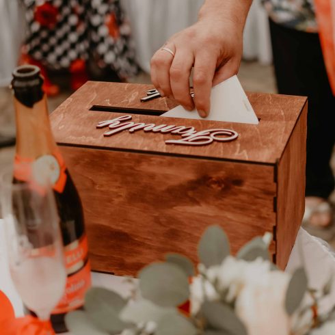 Geld/Brieven box op cadeau tafel van bruiloft waar iemand een envelop in stopt.