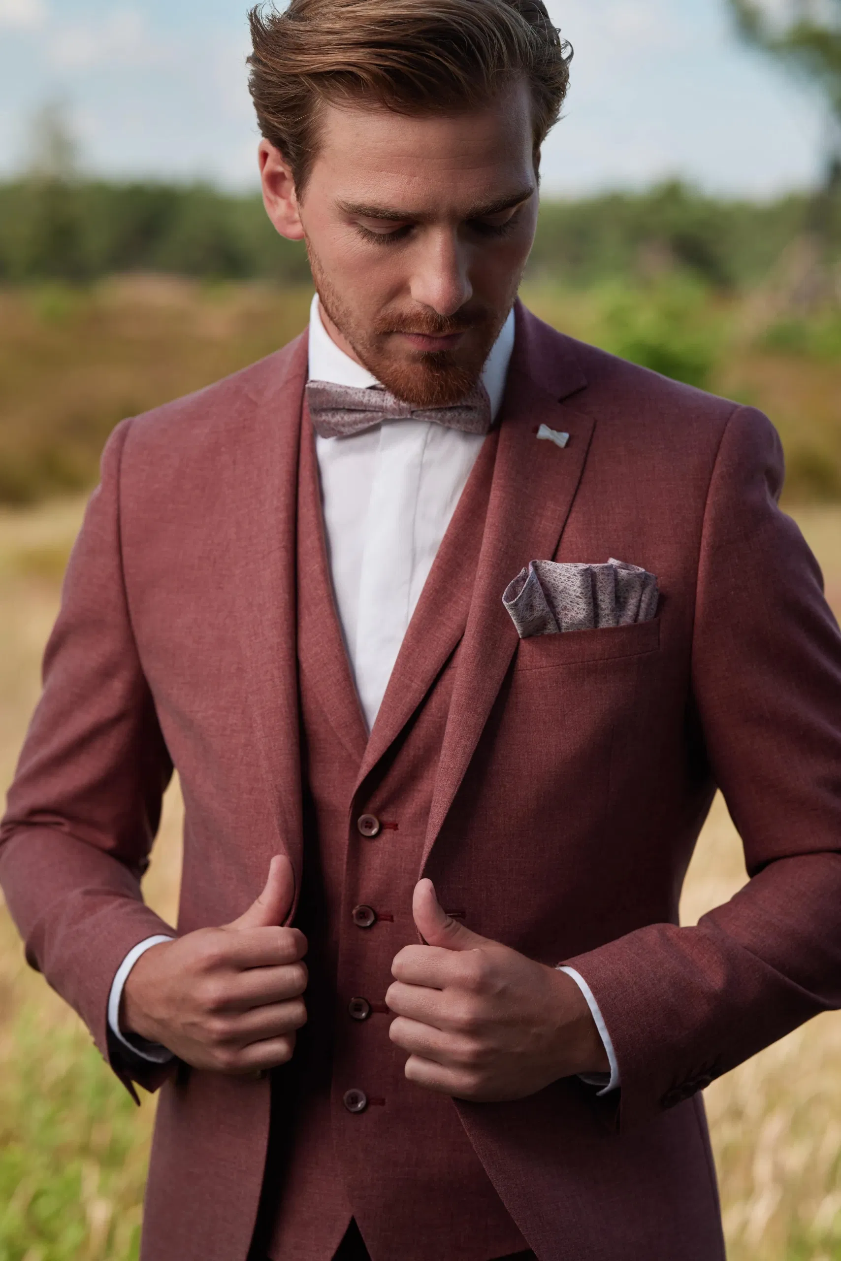 Een bruidegom in driedeling bordeaux trouwpak met vlinderdas van Immediate Fashion