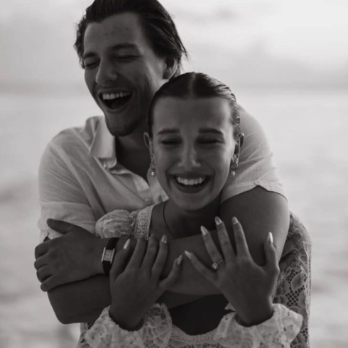 Lachende man houdt vrouw in kanten jurk van achteren vast