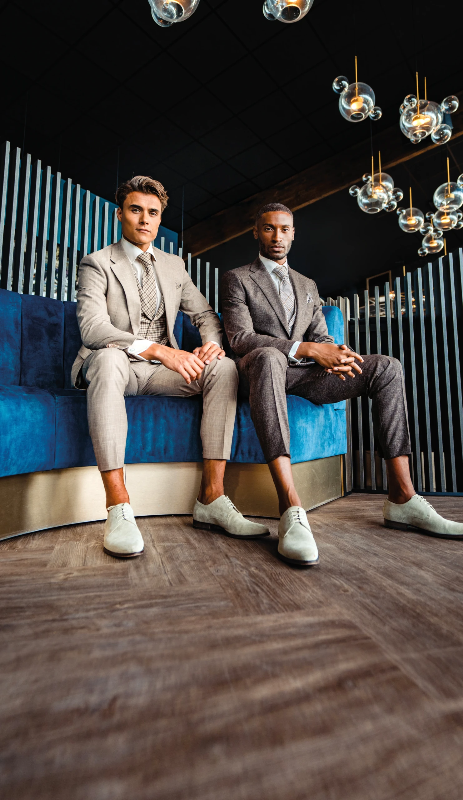 Twee mannen met een 3-delig trouwpak van Roka. Met lichte kleur schoenen zonder sokken.