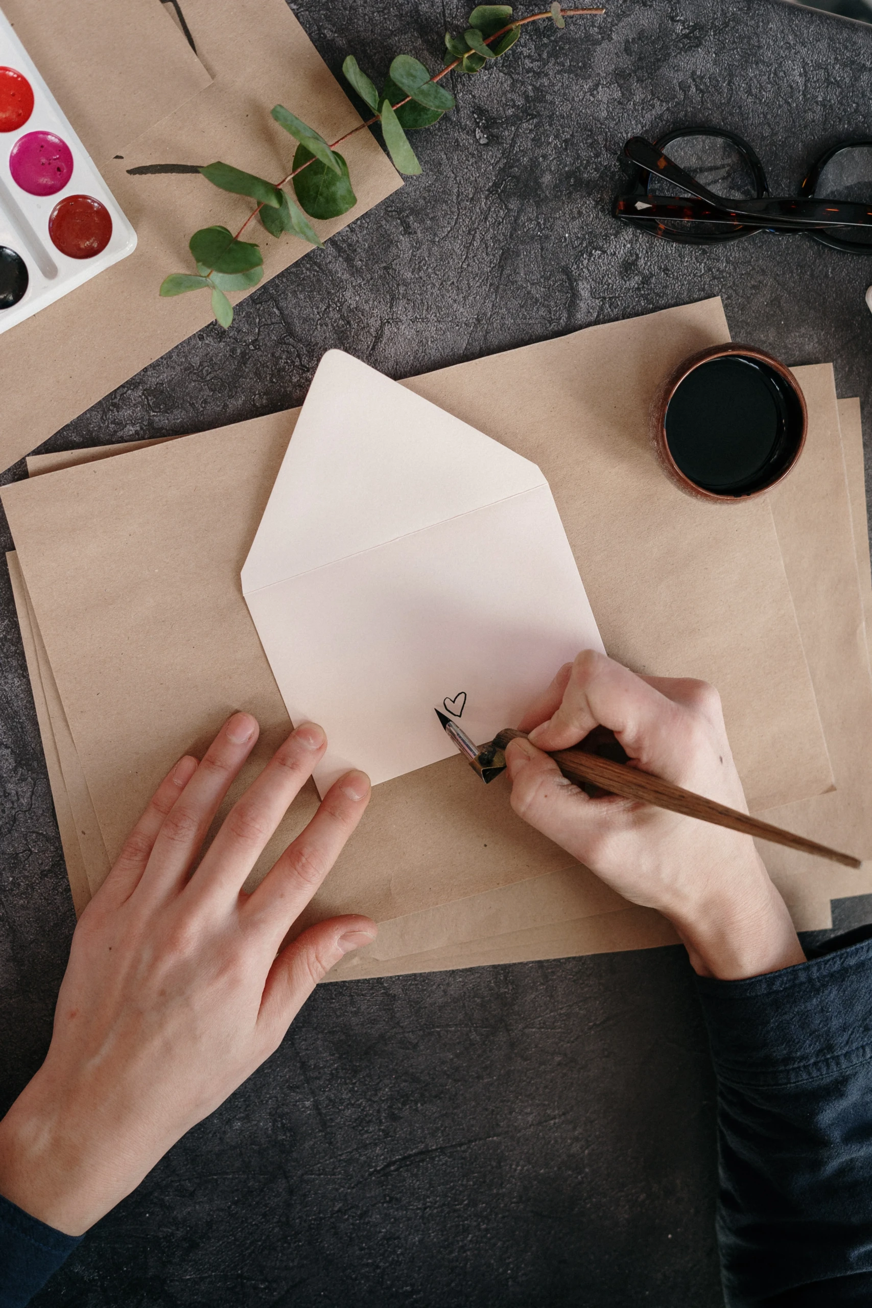 twee handen tekenen een hartje op een envelop