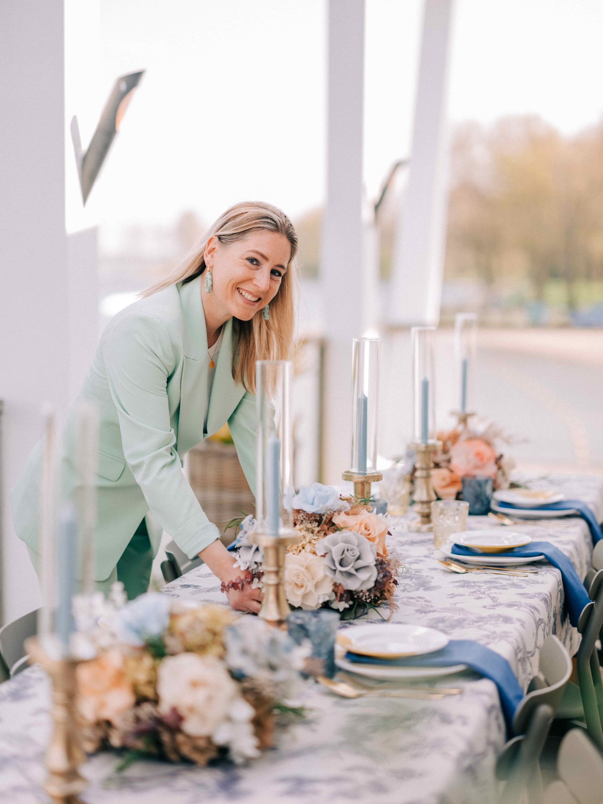 Vrouw in groen colbert maakt een eettafel op voor een bruiloft.
