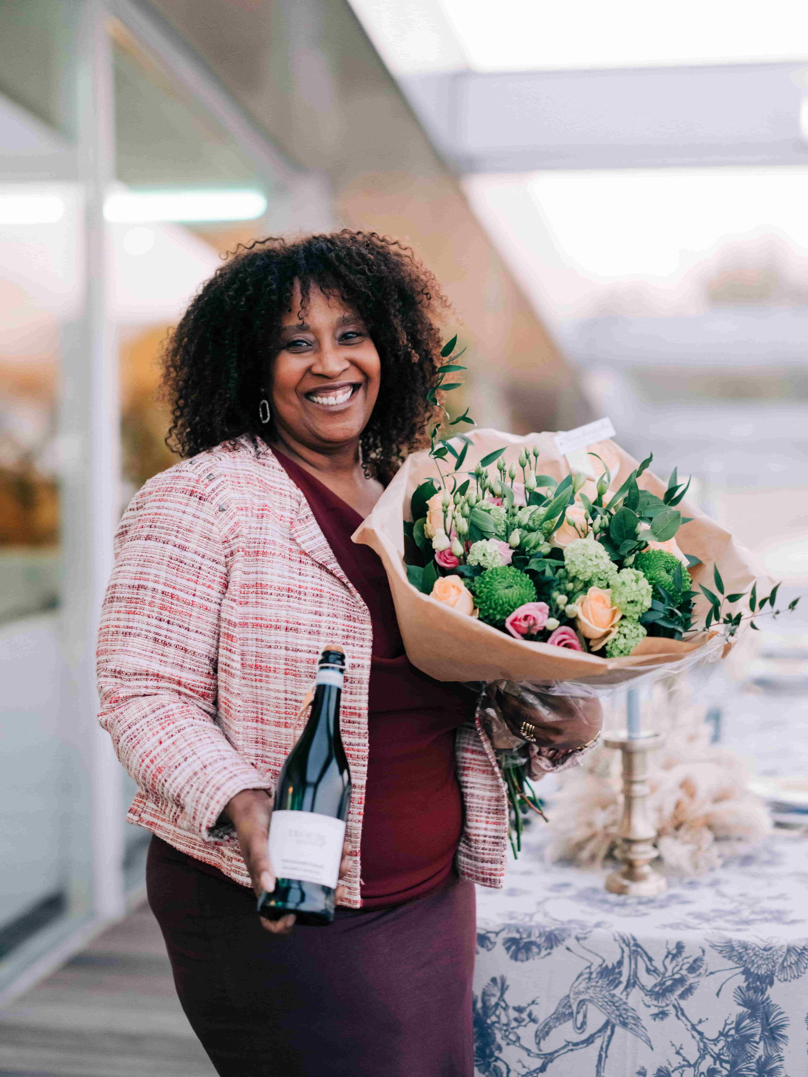 vrouw houdt bruidsboeket enn fles champagne vast