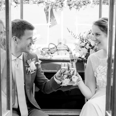 Bruid en bruidegom toosten met champagne glazen achterop de Salonboot De Liefde van Smidtje Luxury Cruises