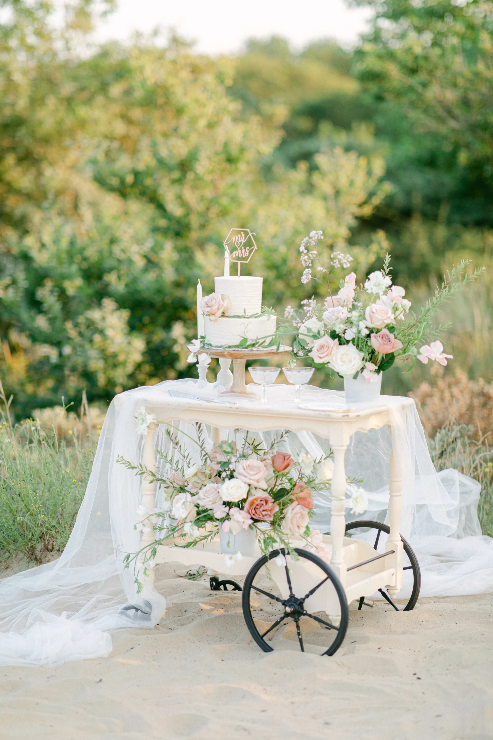 Een wit taartentafel met bloemen in het zand,
