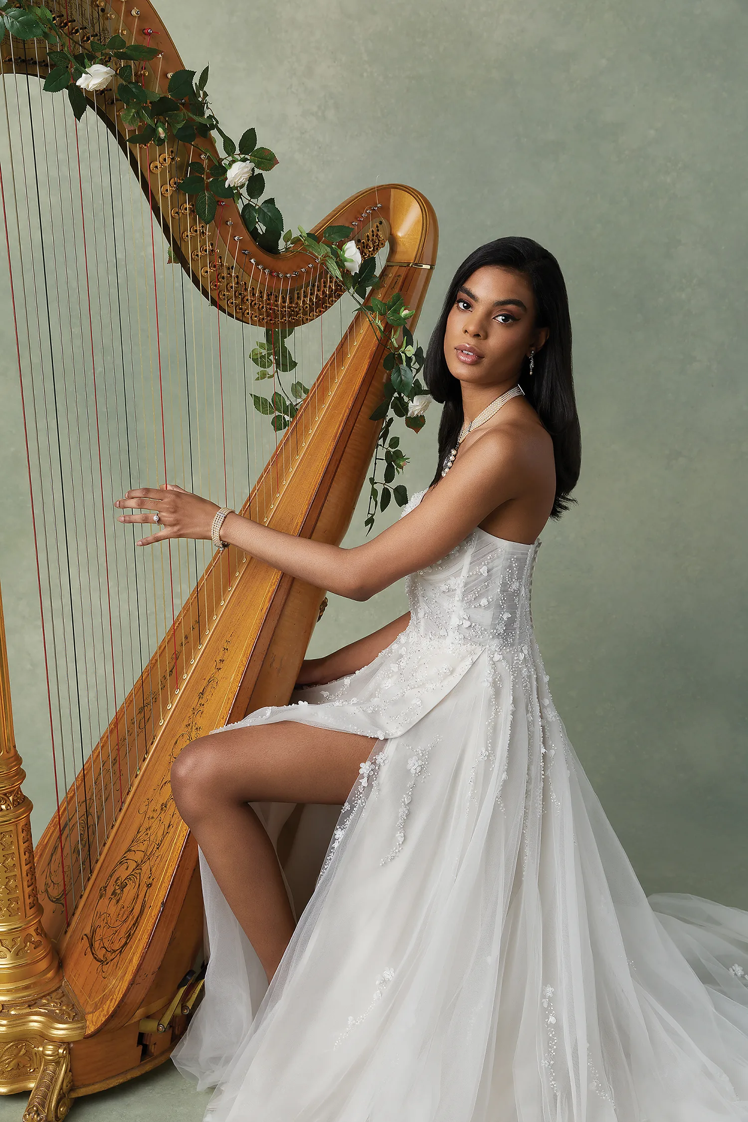 Bruid met donkere huidskleur speelt een harp in een Justin Alexander bruidsjurk