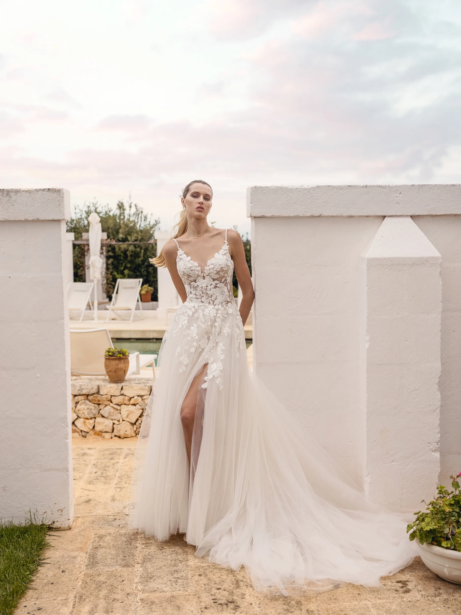 Voor de ingang van het zwembad staat een een bruid in een trouwjurk van Modeca uit de collectie Adorious Collection_Amarynth