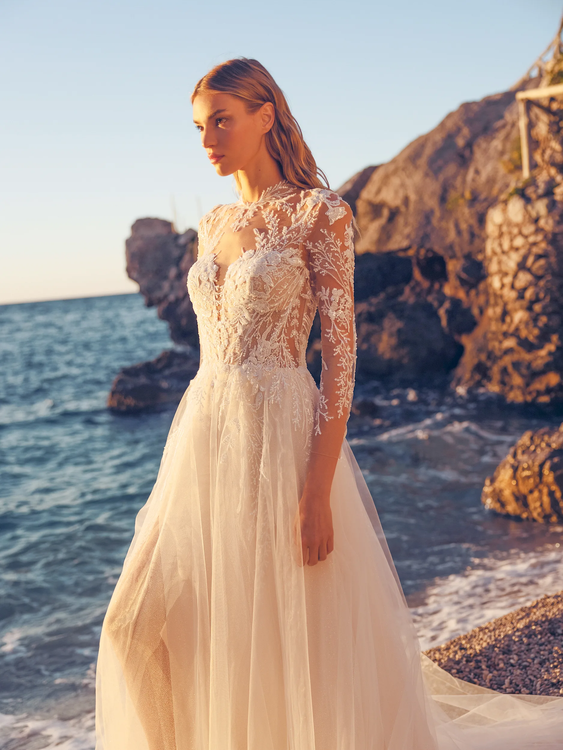 Een bruid op het strand met een ondergaande zon in een witte bruidsjurk van Modeca uit de collectie Blissful Collection_Baylor_