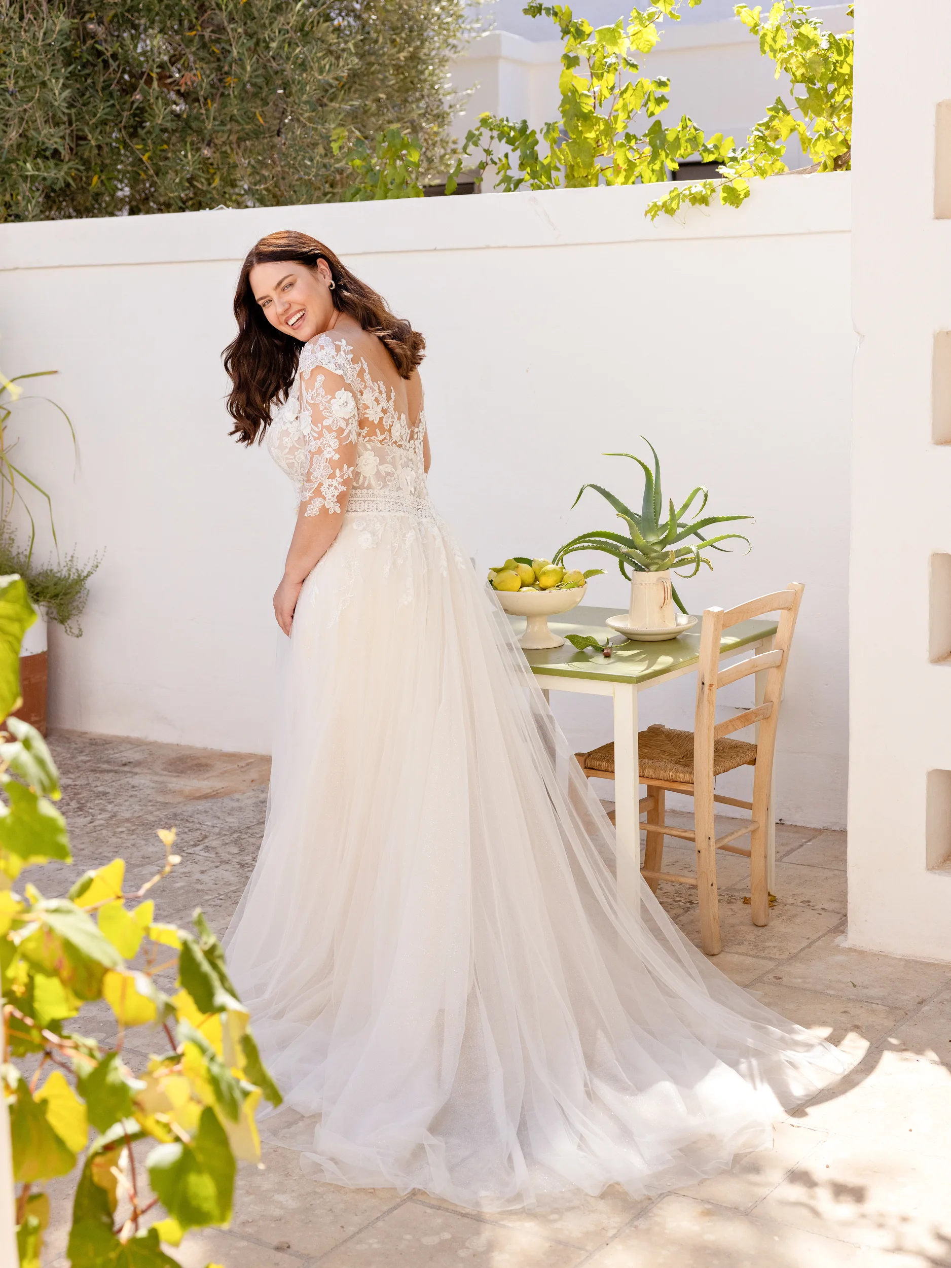 Een voluptueuze bruid draagt een bruidsjurk van Modeca uit de collectie Victoria-Collection_Vivienne. De bruid staat in een binnentuin