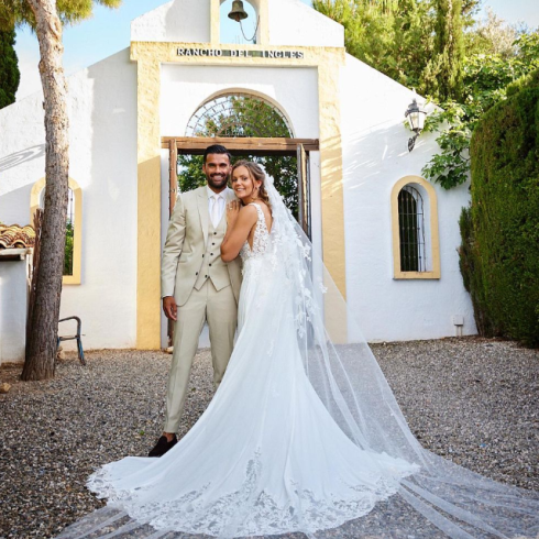 Nederlandse voetbalster Lieke Martens staat voor een Spaans kerkje naast haar man Benjamin in een Pronovias trouwjurk