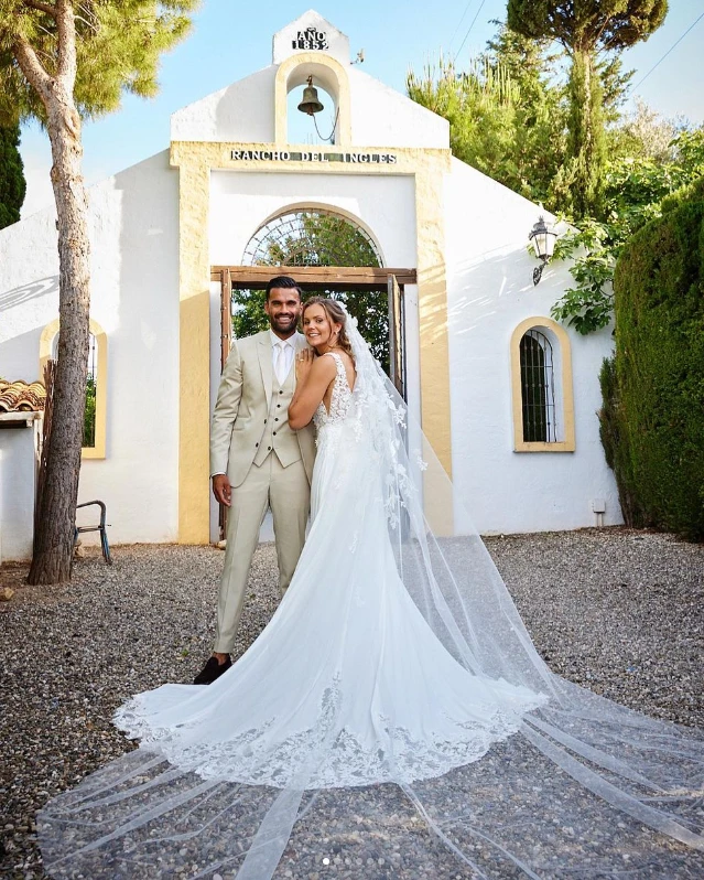 Nederlandse voetbalster Lieke Martens staat voor een Spaans kerkje naast haar man Benjamin in een Pronovias trouwjurk