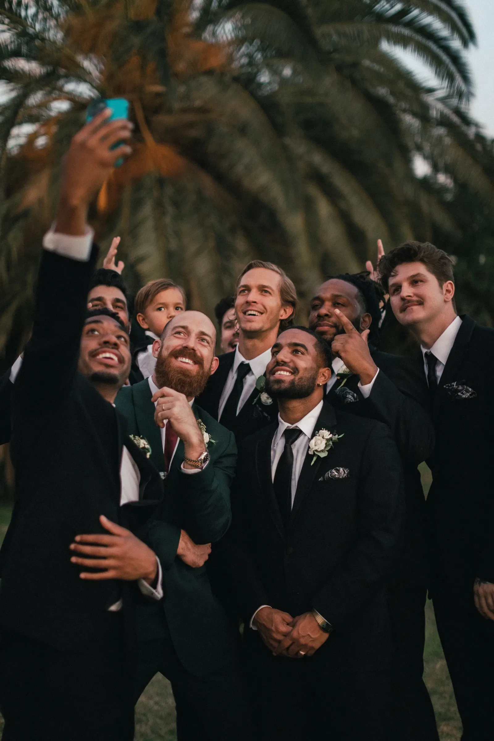 Vrienden of gasten van de bruidegom maken een selfie op de bruiloft voor palmbomen.
