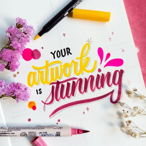 Kleurrijke tekst gemaakt met handlettering, stiften en bloemen.