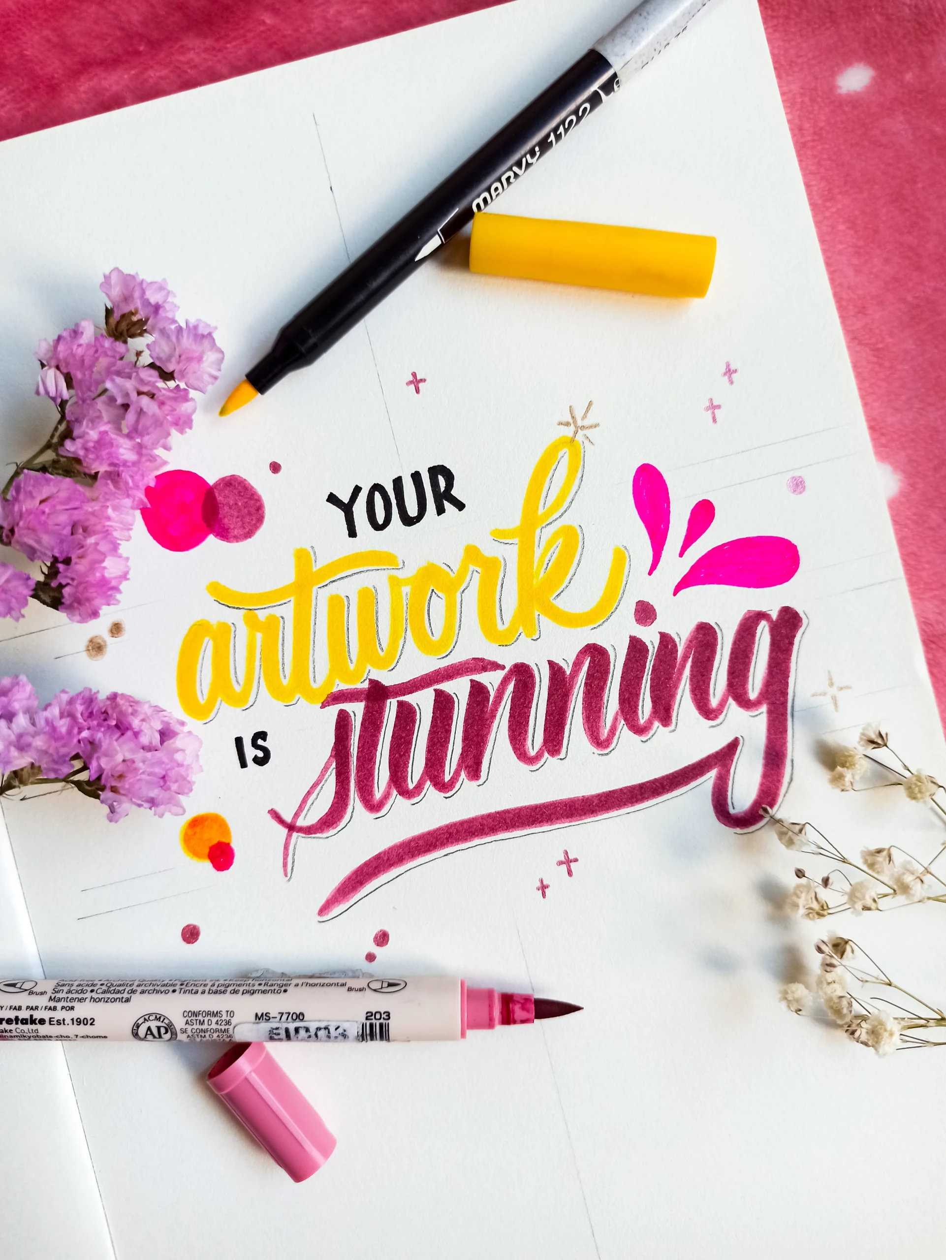 Kleurrijke tekst gemaakt met handlettering, stiften en bloemen.