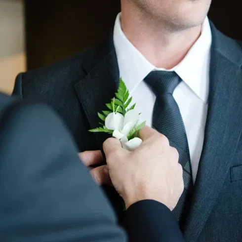 Bruidegom krijgt corsage opgespeld tijdens bruiloft.