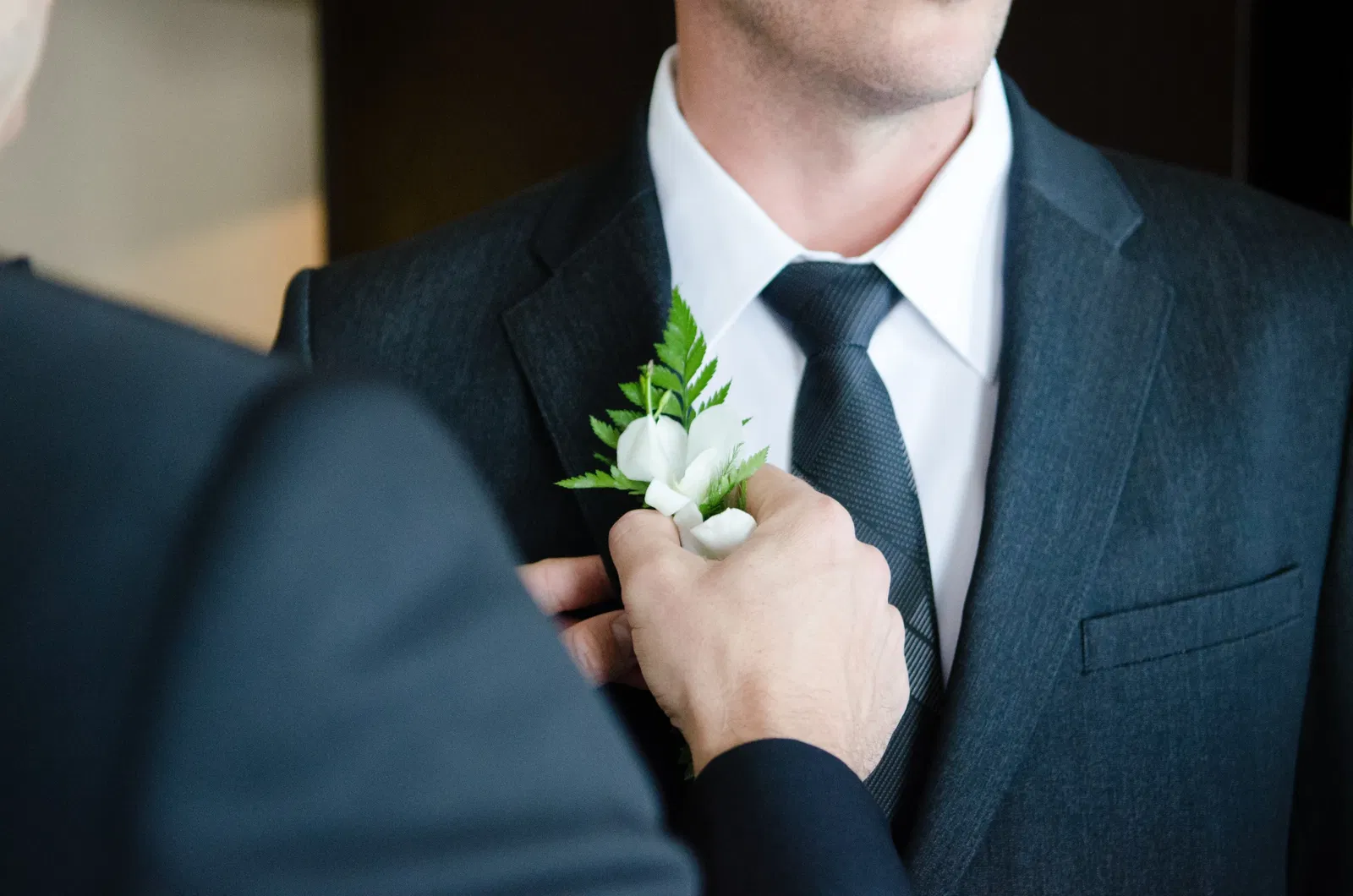 Bruidegom krijgt corsage opgespeld tijdens bruiloft.