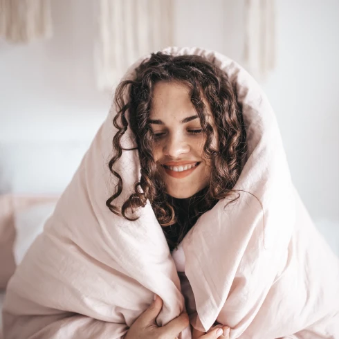 Vrouw kruipt onder dekbed om te ontspannen,