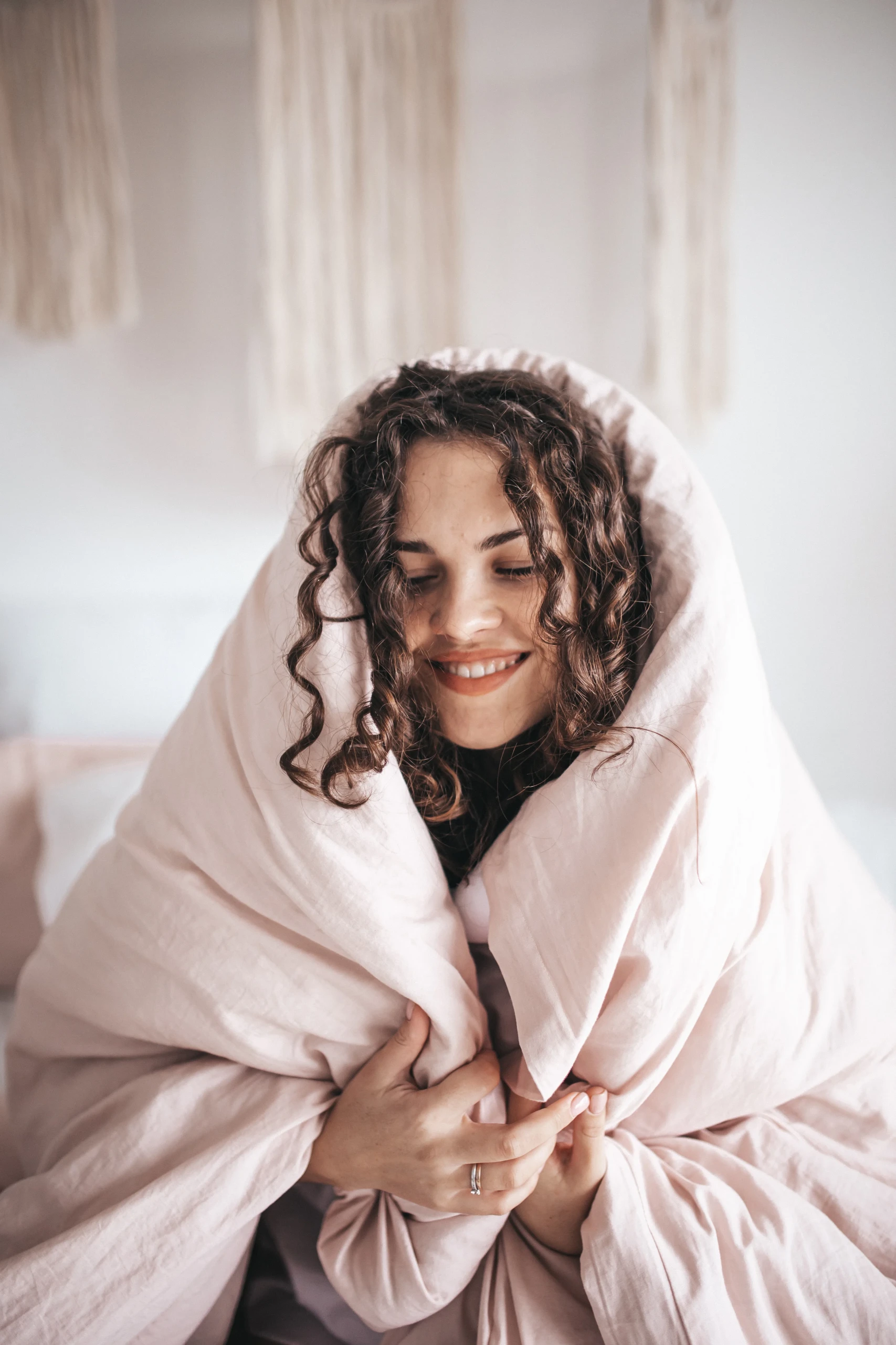 Vrouw kruipt onder dekbed om te ontspannen,