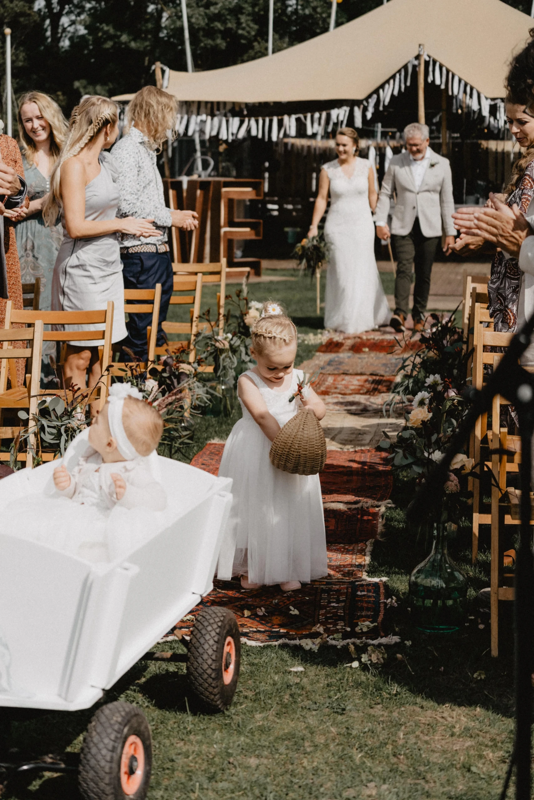 Bruidsmeisje strooit bloemen op festival bruiloft, bruid en haar vader zijn onderweg naar de ceremonie.