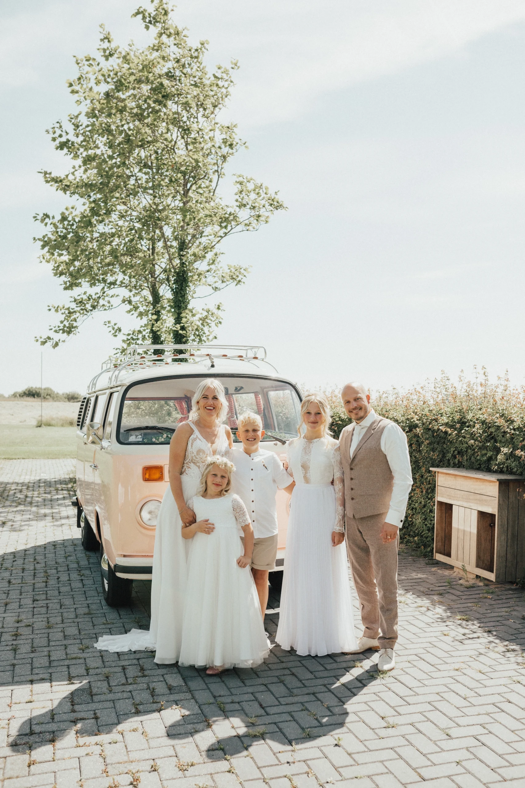 Gezin staat op bruiloft voor een Volkswagen busje.