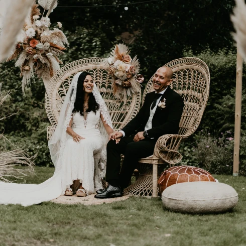 Bruidspaar op festival boho bruiloft zitten op stoelen bij de ceremonie.