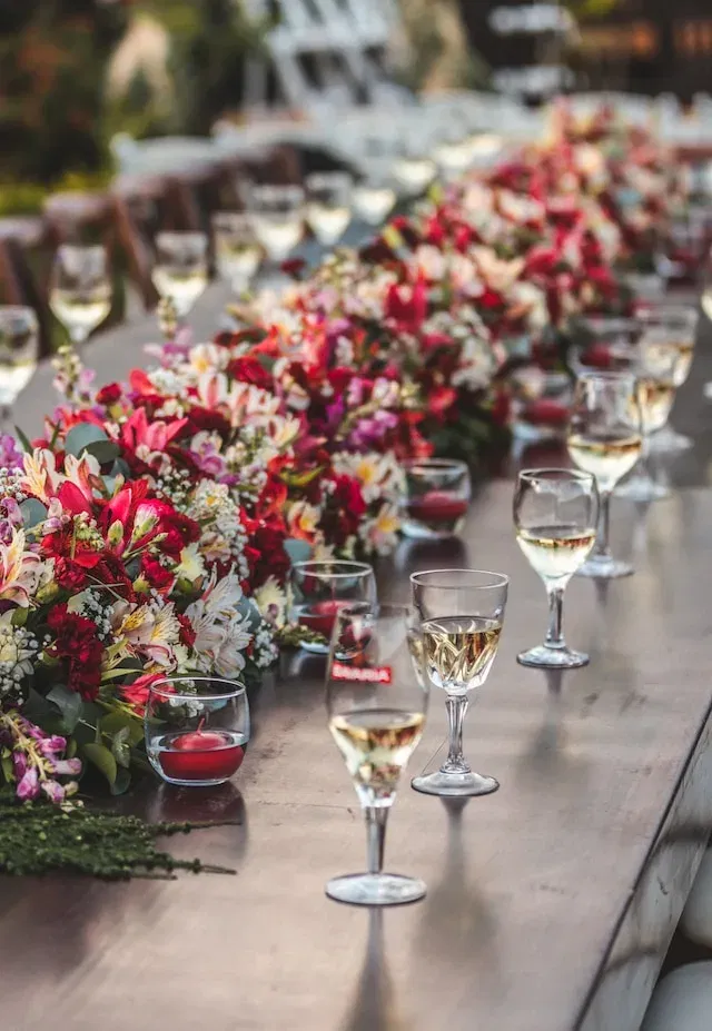 Een tafel met bloemen en drankjes op een bruiloft