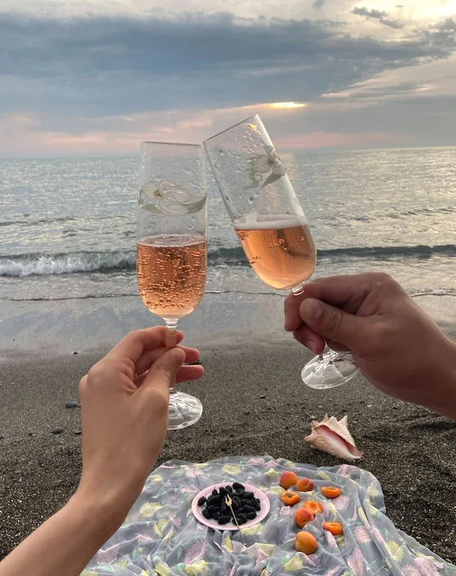 Stel dat samen op strand aan het picnicken is, met een glas rosé.