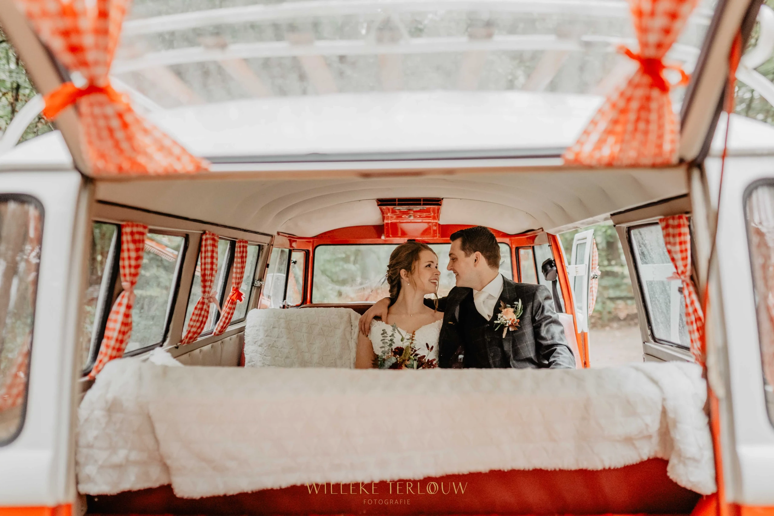 Bruidspaar in rood oldtimer Volkswagen busje.