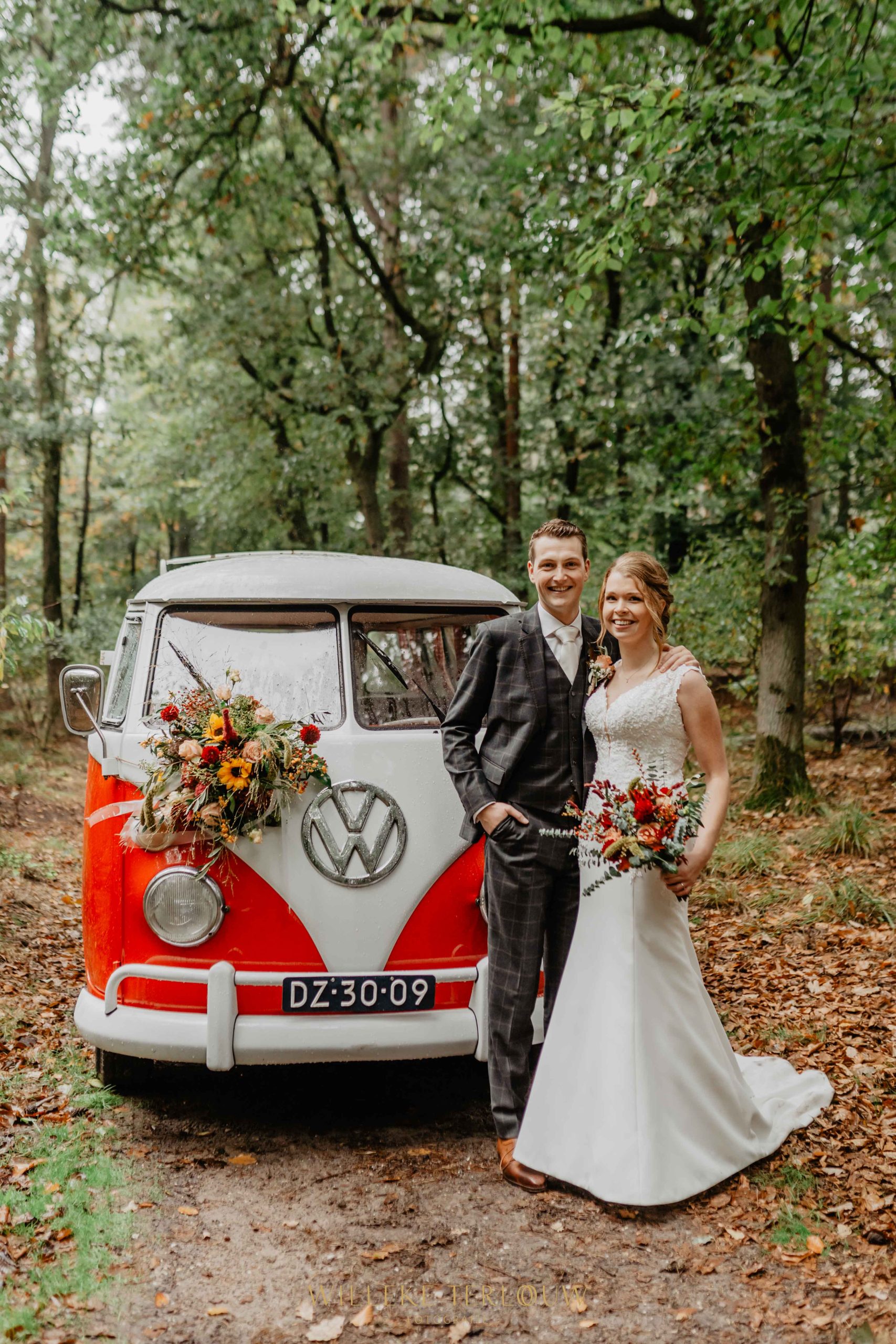 Bruidspaar voor hun trouwauto, een oldtimer Volkwagen busje.