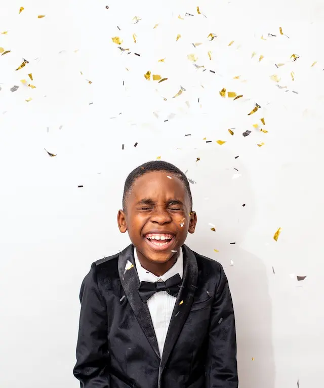 Jongetje in net pak met strik en gouden confetti.