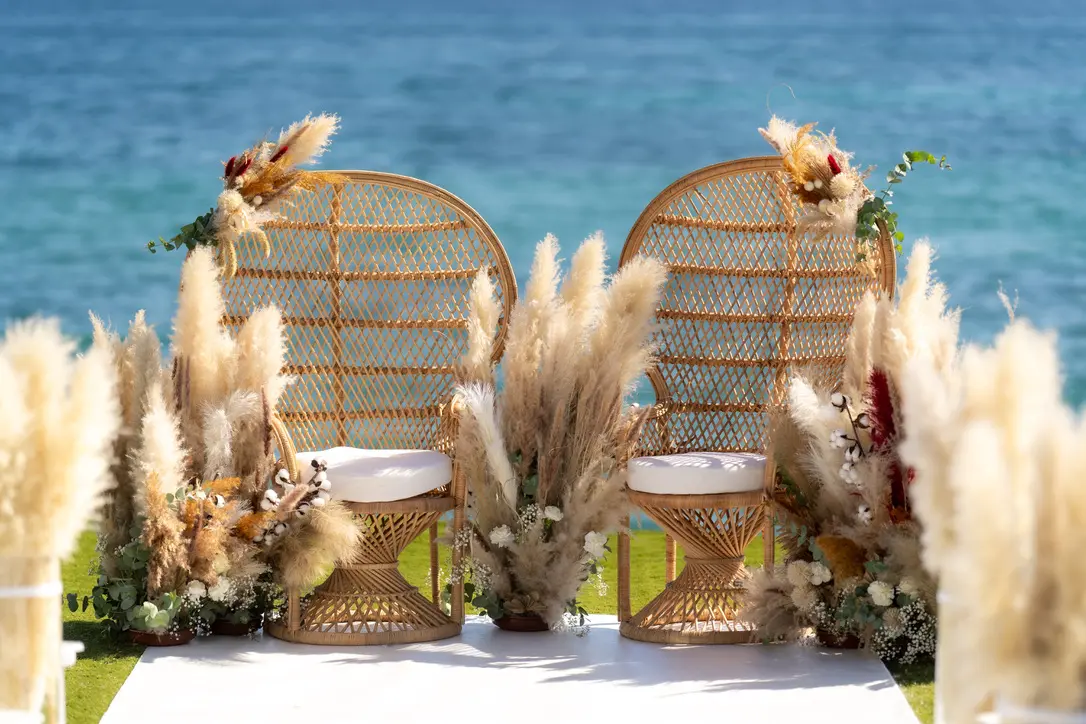 twee grote rieten rotan stoelen voor bruidspaar aan het strand voor een strandbruiloft.