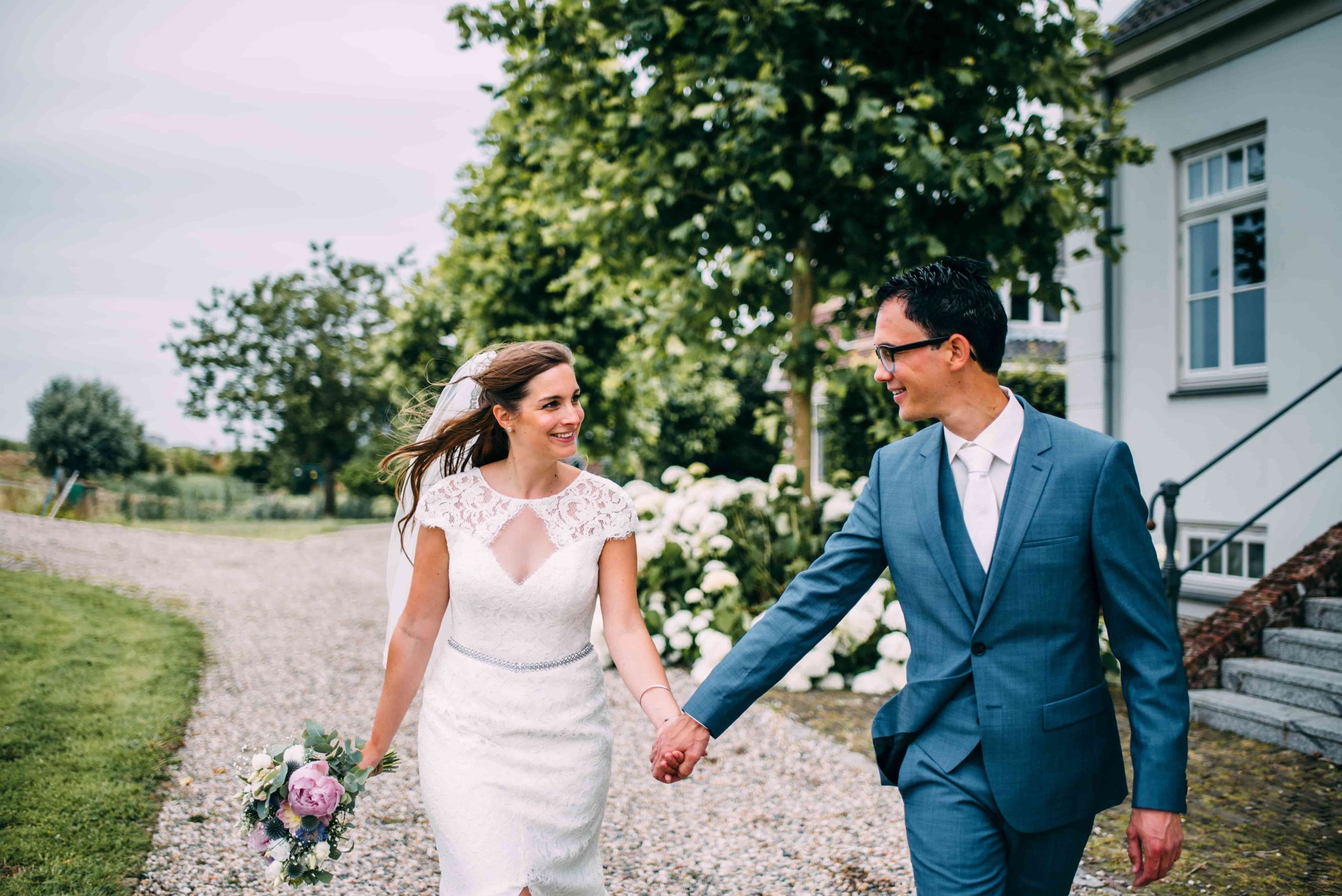 Gelukkig bruidspaar dat hand in hand loopt.