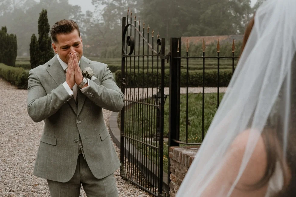 Bruidegom kijkt vol emotie naar zijn bruid tijdens first look moment.