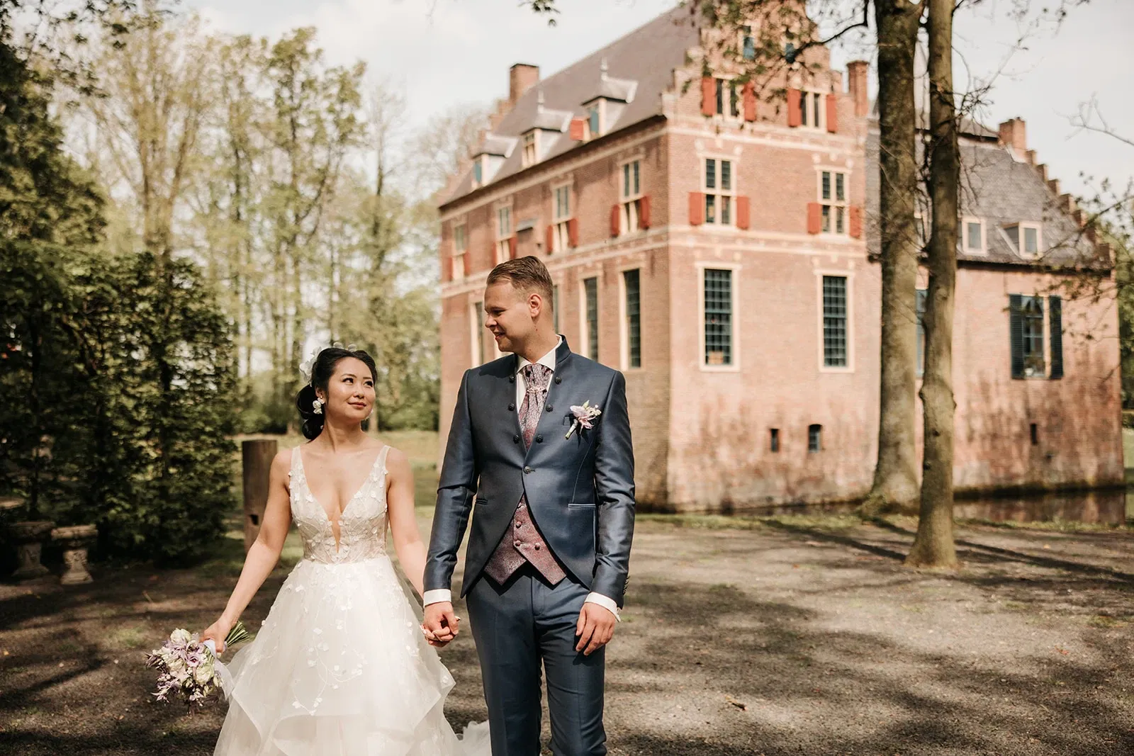 Bruidspaar met trouwlocatie kasteel Wijenburg op achtergrond